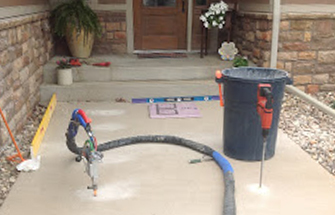 View of the front entrance walkway of a residential home with a few simple tools for the concrete lifting process on the sidewalk.