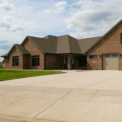 Front view of a beautiful and modern brown-brick, 2-story residential home in a classy neighborhood with a large, quality concrete driveway